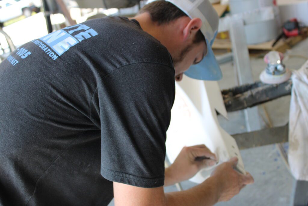 Man wearing Absolute Marine shirt and had, working closely on boat.