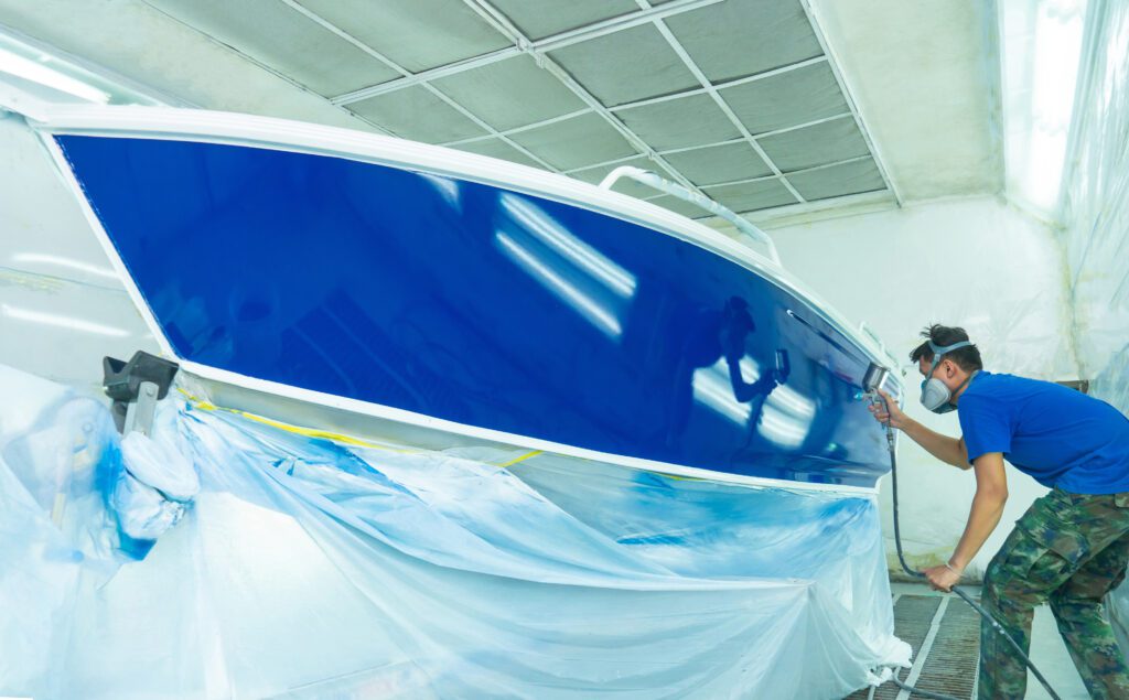 Repairman fixing by painting boat body and painting boat using spray gun