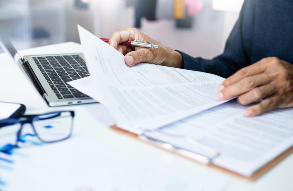 Businessman reviewing document reports at office workplace with computer laptop. legal expert, professional lawyer reading and checking financial documents or insurance contract